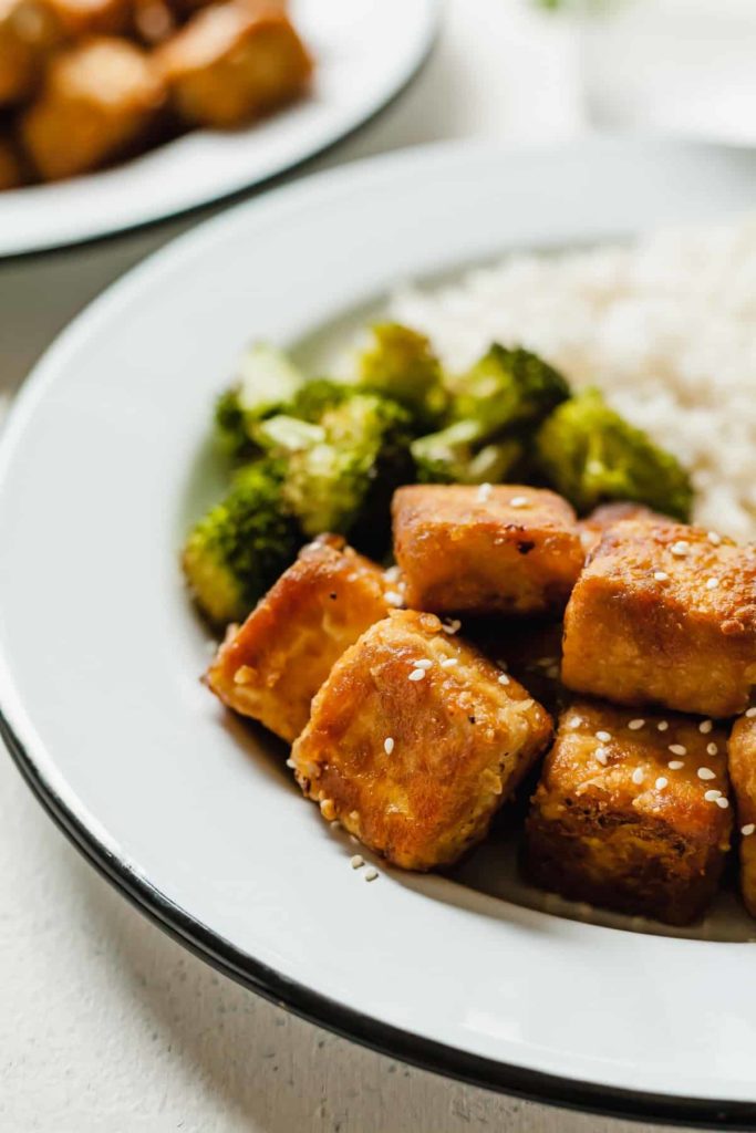 crisp tofu on a white plate with broccoli and rice