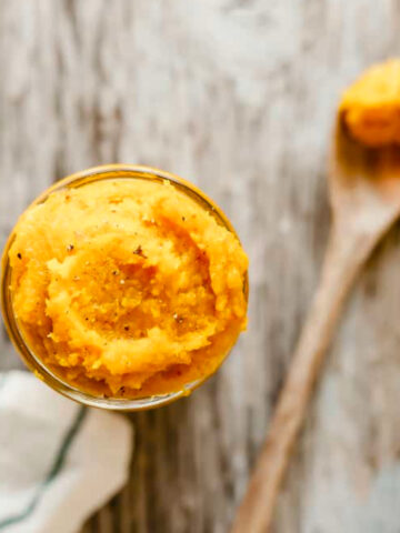 top view of squash puree in a cup with a spoon of squash puree