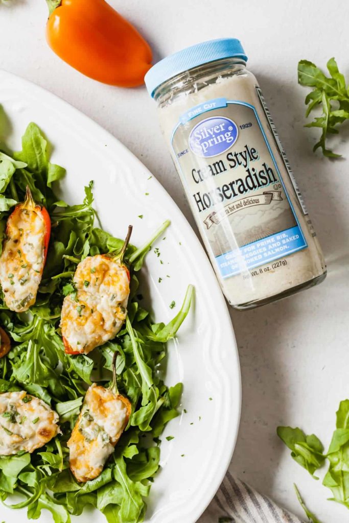 a bottle of horseradish next to cream cheese stuffed mini peppers