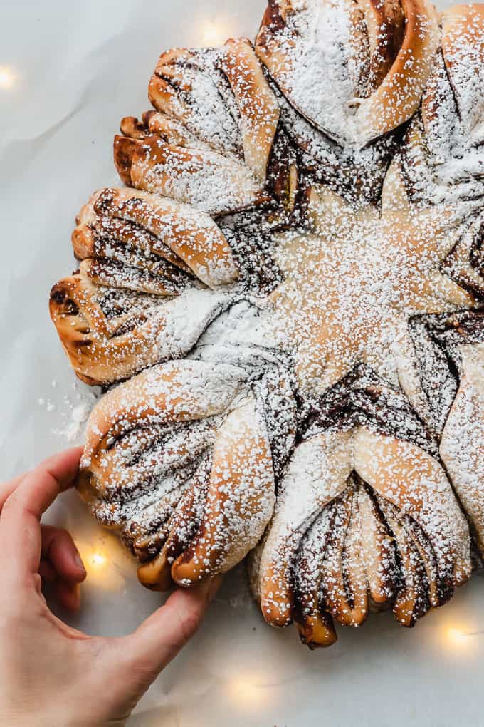 a hand grabbing one piece of chocolate pistachio christmas star bread