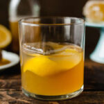 gold rush cocktail in a glass with a lemon twist