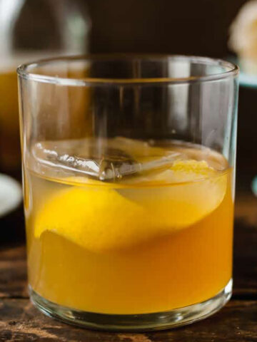 gold rush cocktail in a glass with a lemon twist