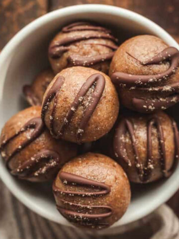 cardamom rose energy balls in a white bowl on a wood table.