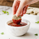 hand dipping homemade veggie nugget into spicy ketchup