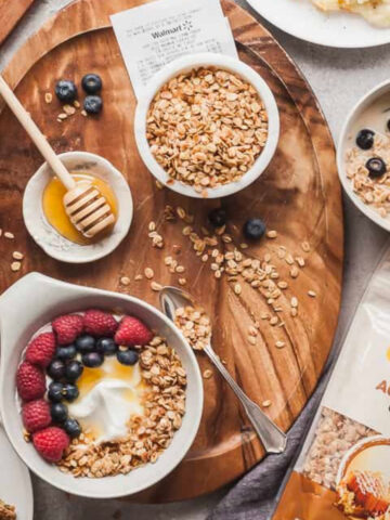 flatlay photo of gluten free breakfast ideas including almond butter apple rings, a yogurt bowl, bowl of granola, and eggs.