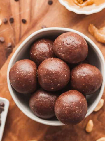 a small bowl of chocolate peanut butter protein balls with chocolate chips, peanuts, and peanut butter.