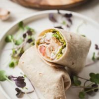 white plate with a vegetarian chciken caesar wrap cut in half