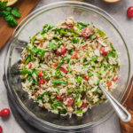 A bowl of vegan orzo pasta salad with a spoon in it.