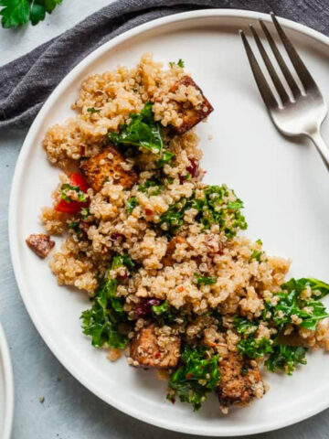 vegan quinoa salad with balsamic tofu on a white plate with fork and napkin.