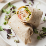 a chik'n caesar wrap cut in half on a white plate