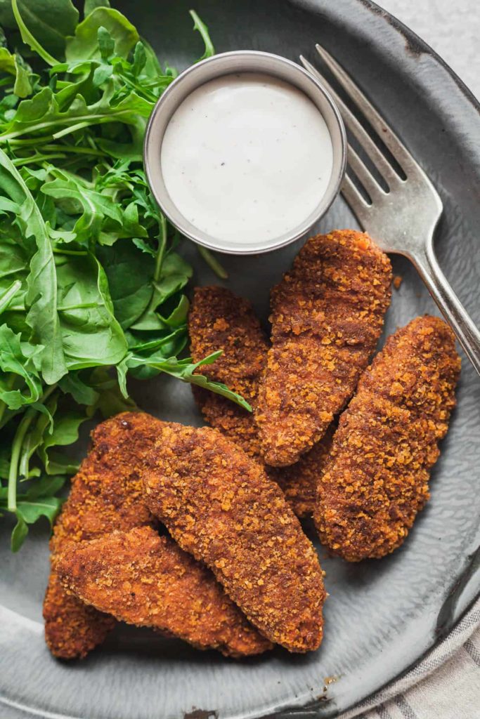 spicy meatless tenders on a plate with arugula and ranch