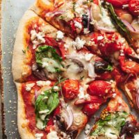 greek pizza sliced on a pan