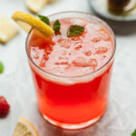 a glass of strawberry lemonade with mint and lemon