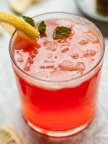 a glass of strawberry lemonade with mint and lemon