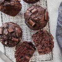 chocolate zucchini muffins on a cooling rack with a knife