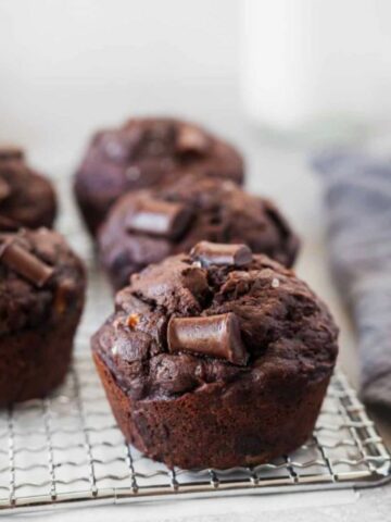Vegan chocolate zucchini muffins on a cooling rack.