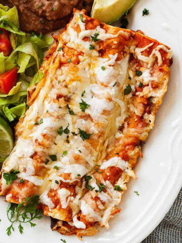 three cheese enchiladas on a plate with salad and beans