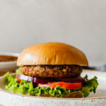 a lentil burger on a bun with lettuce, tomato, and onion