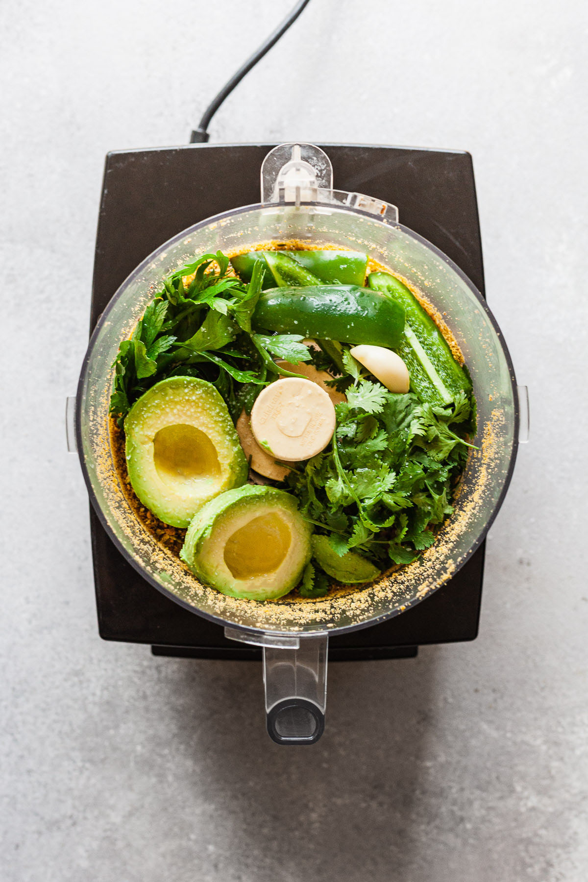 avocado sauce ingredients in a food processor before chopping