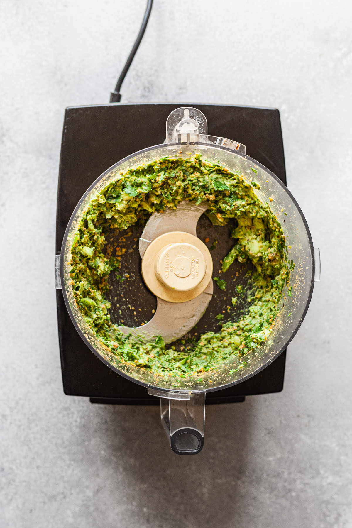 green avocado sauce in a food processor after chopping