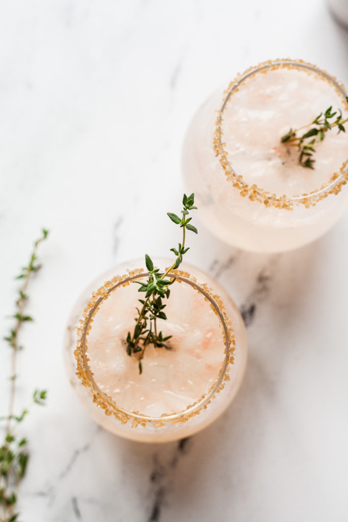 overhead photo of two grapefruit vodka drinks with fresh thyme