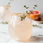 a sparkling greyhound cocktail with a sprig of thyme on a marble table