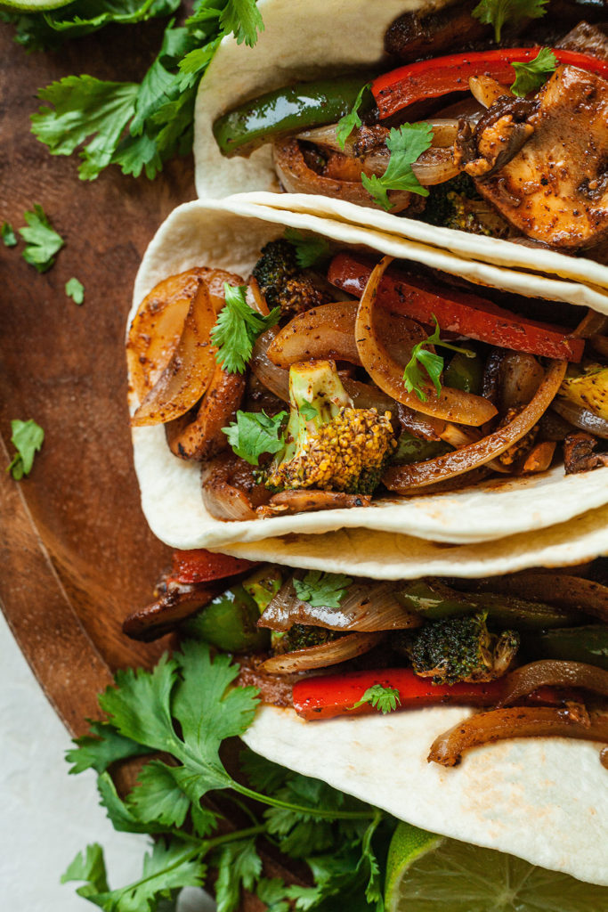 three veggie fajitas on a wood platter with cilantro