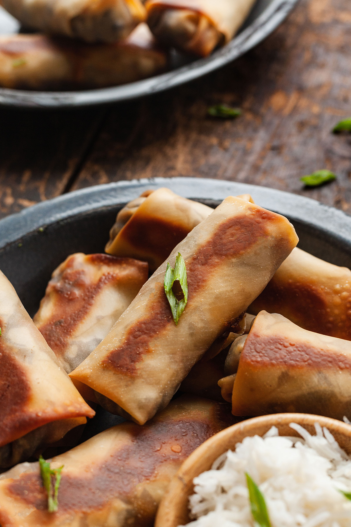 baked vegetarian egg rolls on a blue plate with a small bowl of rice.