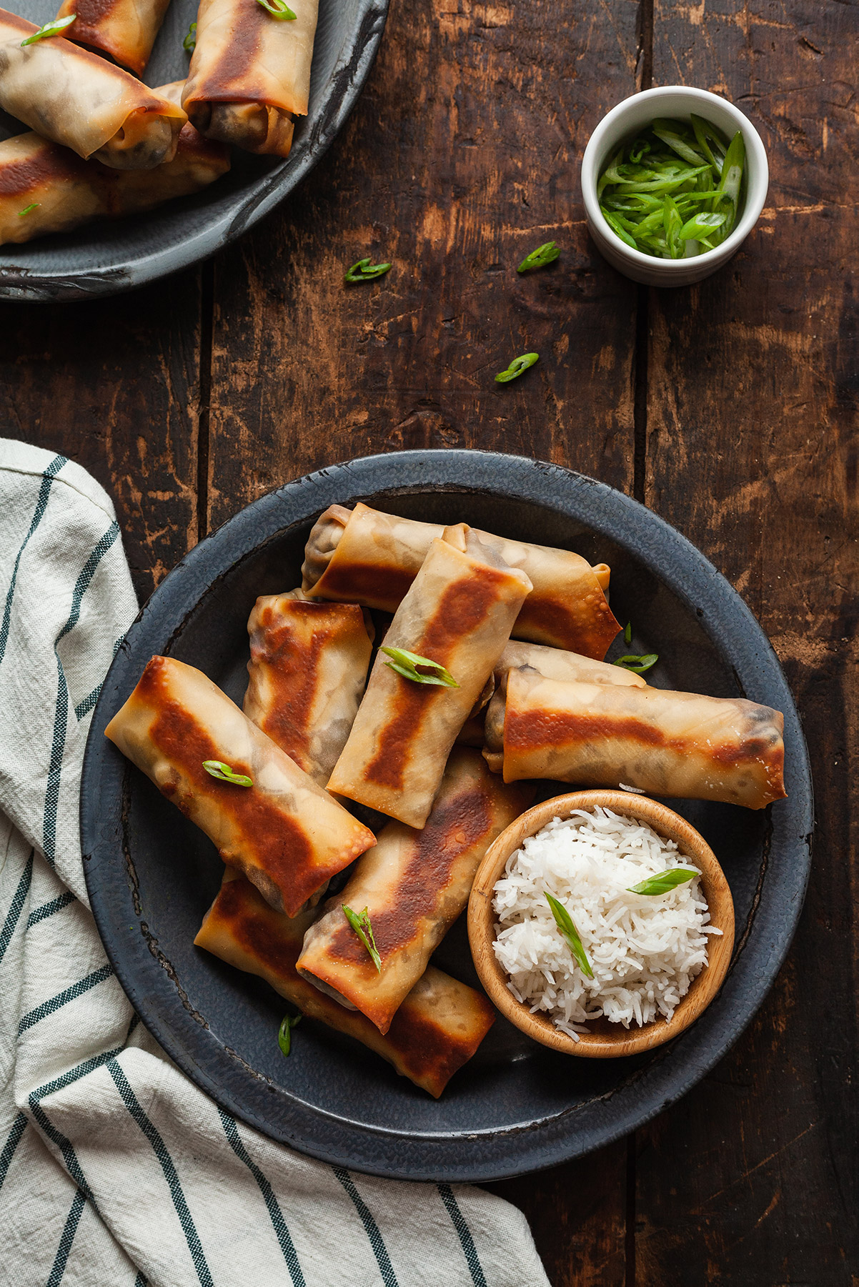 vegetarian southwest egg rolls on a blue plate with white rice in a wood bowl.