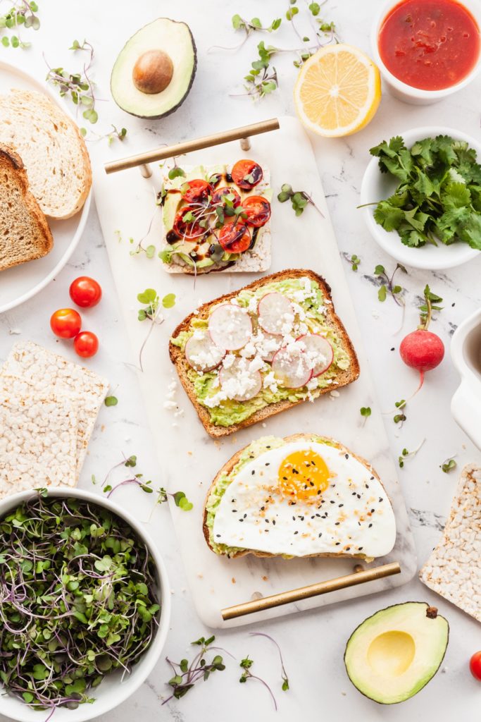 three slices of avocado toast with different toppings