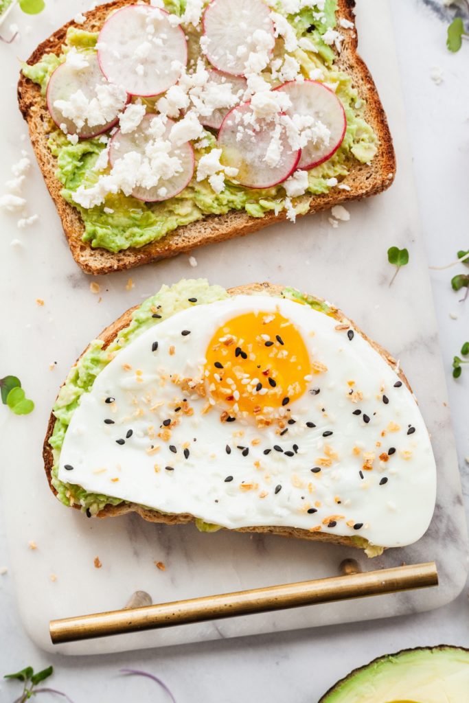 close up photo of a slice of avocado toast topped with a fried egg and everything but the bagel seasoning