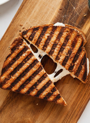 a grilled cheese sandwich cut in half on a wood cutting board