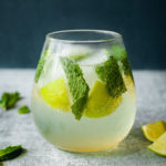 glass of a mojito mocktail from the side with mint and limes