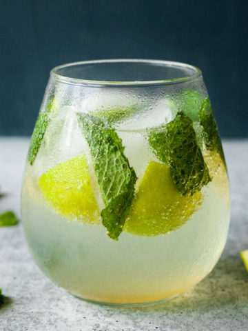 glass of a mojito mocktail from the side with mint and limes