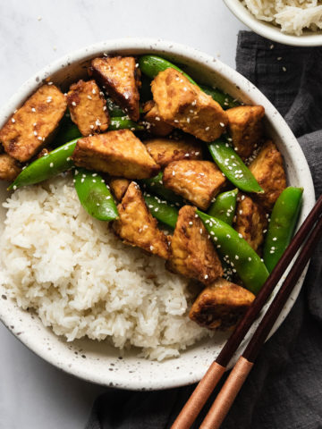 easy stir fried tempeh in a bowl with white rice and chopsticks