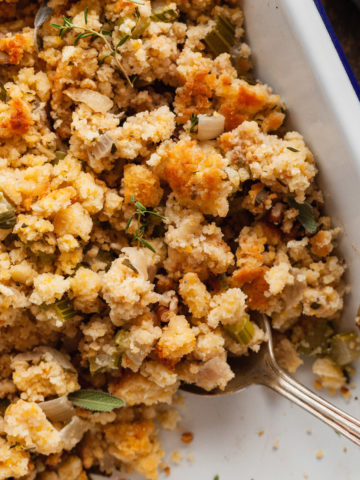 a pan of cornbread stuffing with a serving spoon in it