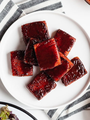 bbq tofu on a white plate with a striped towel