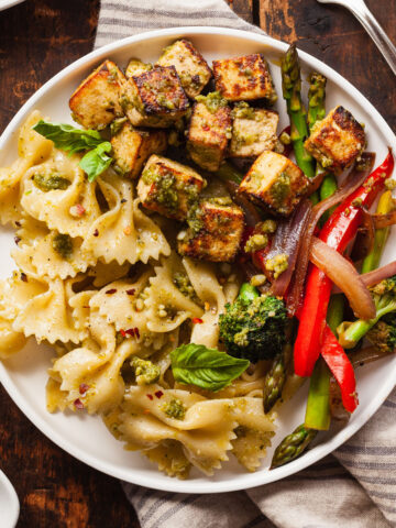 a plate of pesto tofu, balsamic vegetables, and bowtie pasta