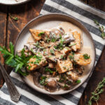 a plate of creamy mushroom tempeh on a striped napkin