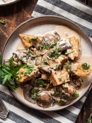 a plate of creamy mushroom tempeh on a striped napkin