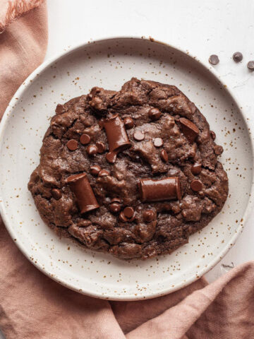 a single serve vegan chocolate brownie cookie on a plate with a pink napkin