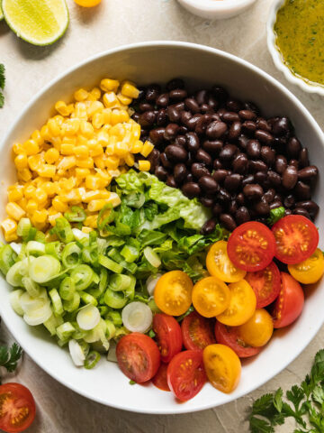 southwest salad ingredients in a white bowl with other veggies around