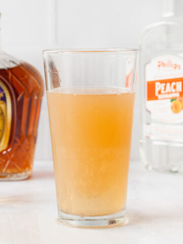 a tall pint glass filled with a vegas bomb shot surrounded by liquor and shot glasses