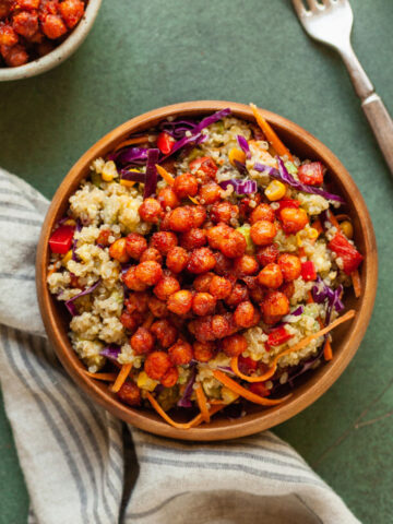 a bowl of rainbow quinoa salad with a linen napkin and fork