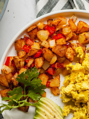 air fryer home fries on a plate with avocado and scrambled tofu