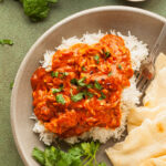 a plate of vegan butter chicken with rice and naan