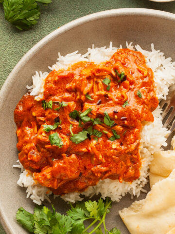 a plate of vegan butter chicken with rice and naan