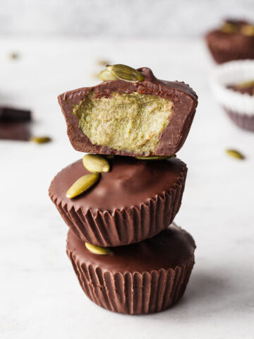 a stack of three pumpkin butter cups with the top one cut in half showing the green pumpkin butter inside