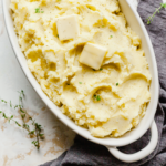 a platter of mashed potatoes with pats of butter on top