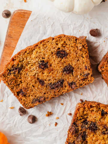 three slices of pumpkin chocolate chip loaf on a cutting board